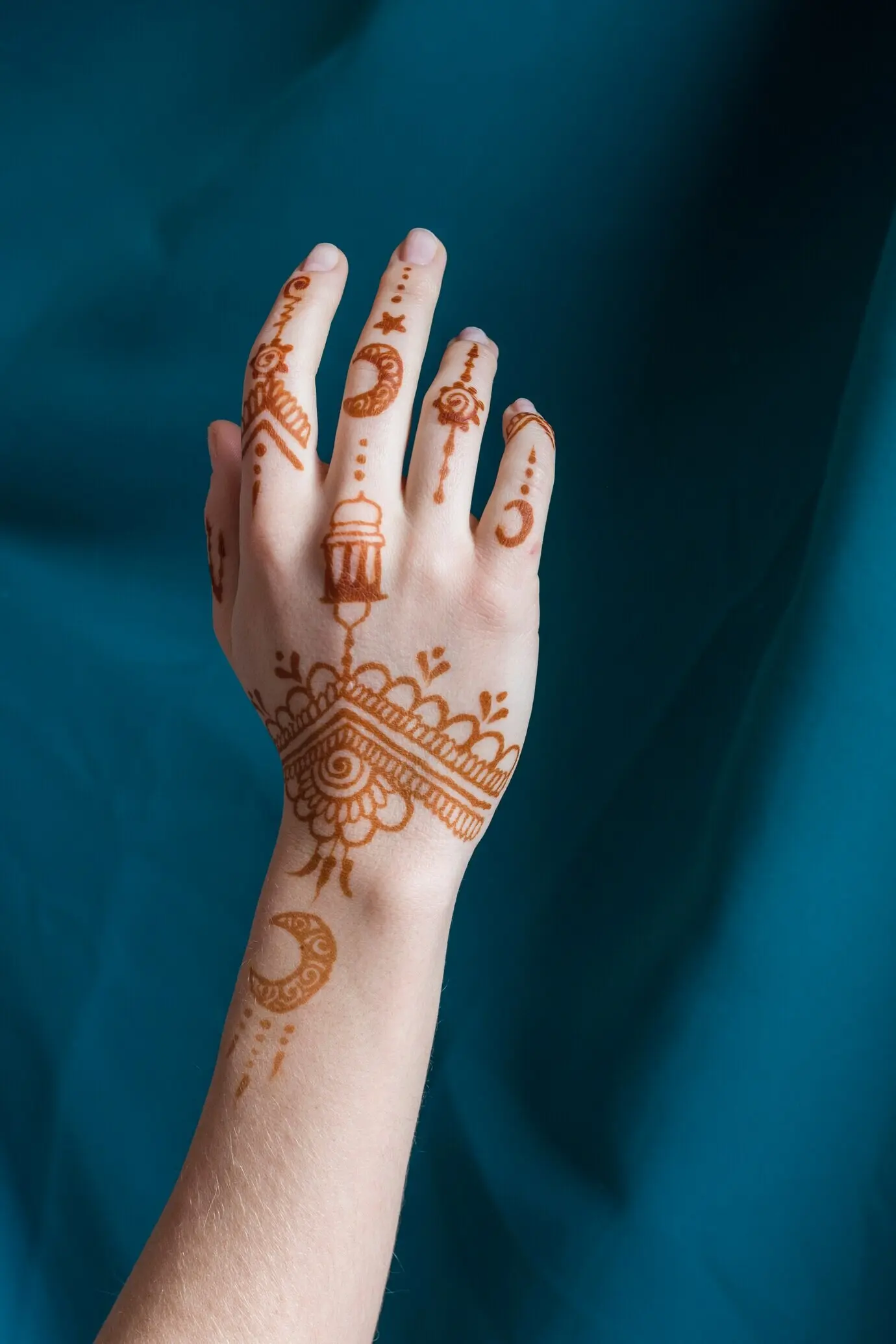 Hand einer Frau mit Mehndi in der Nähe eines blauen Textils
